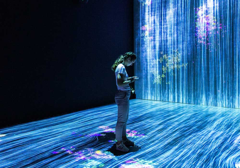 A girl standing inside a exhibition-room filled with blue lights.